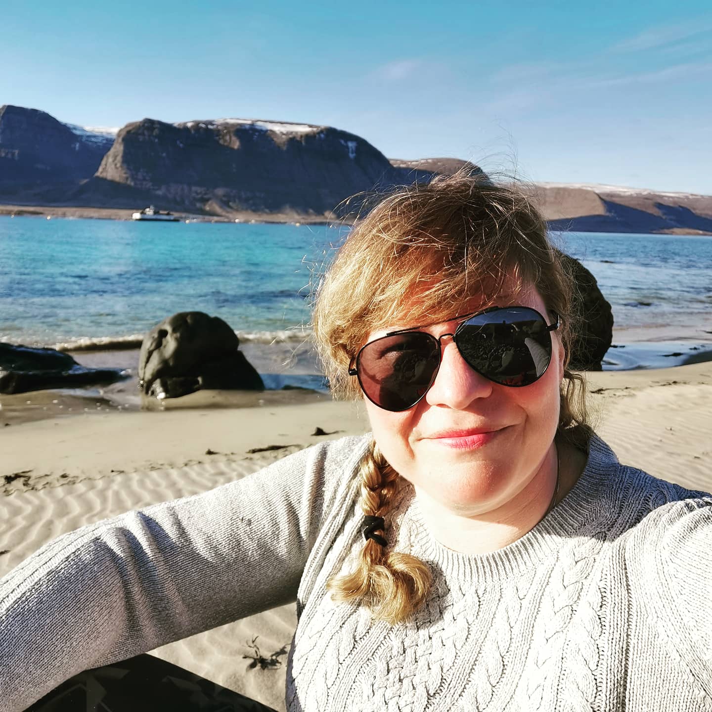 Gréta situr í fjöru með sjó og fjöll í baksýn Gréta situr í fjöru með sjó og fjöll í baksýn