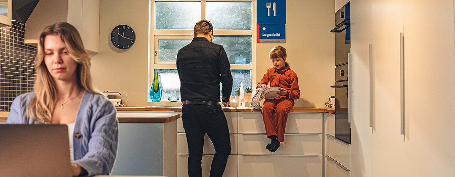 Young woman on laptop, her family in the background